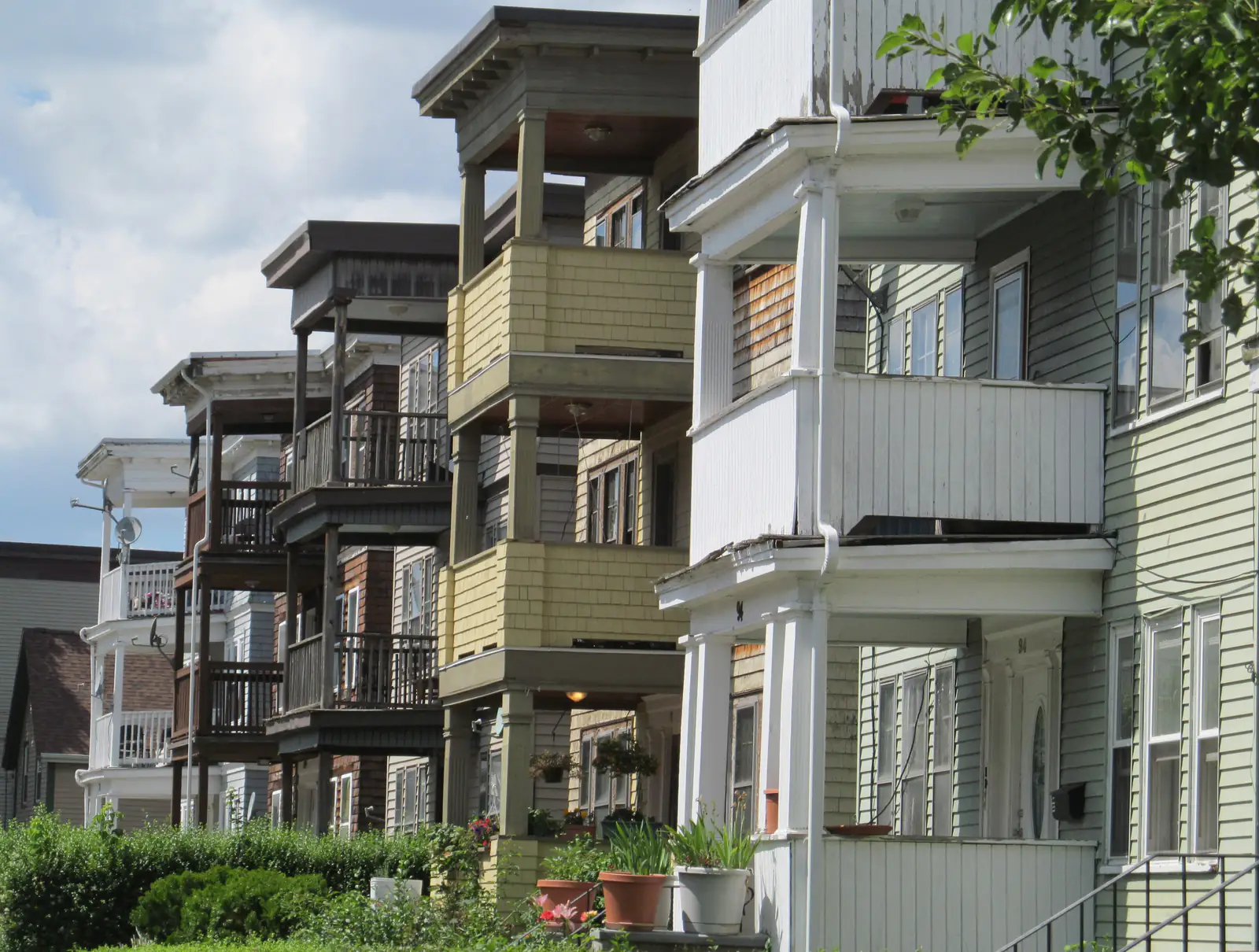 A row of triple-decker houses with stacked porches on a residential street in Boston, Massachusetts